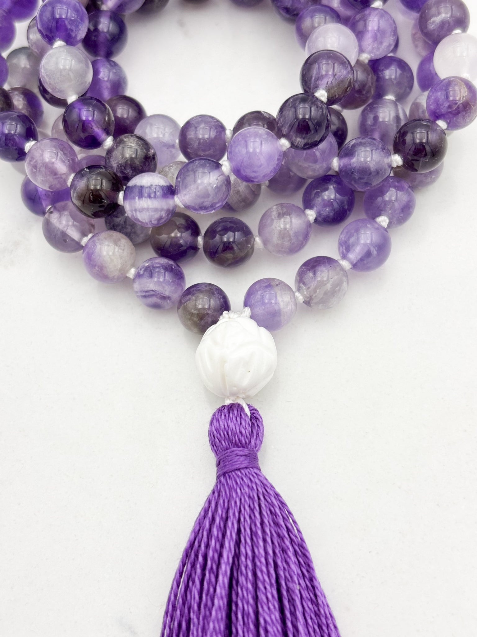 amethyst gemstone mala with carved tridacna shell guru bead and purple tassel | radiant malas | handmade in boulder, colorado