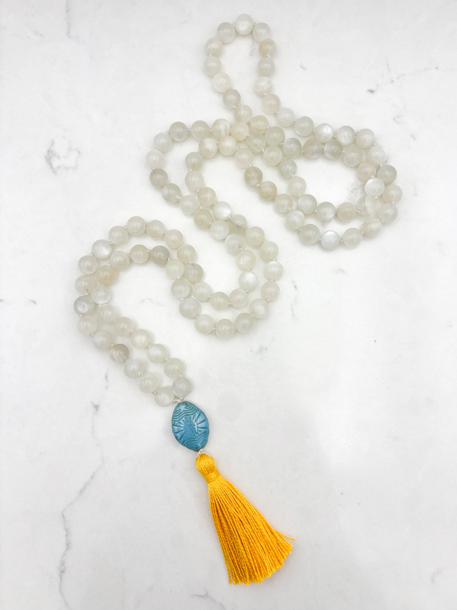 moonstone gemstone mala necklace with carved blue glass guru bead and yellow tassel | handmade in boulder, colorado | radiant malas