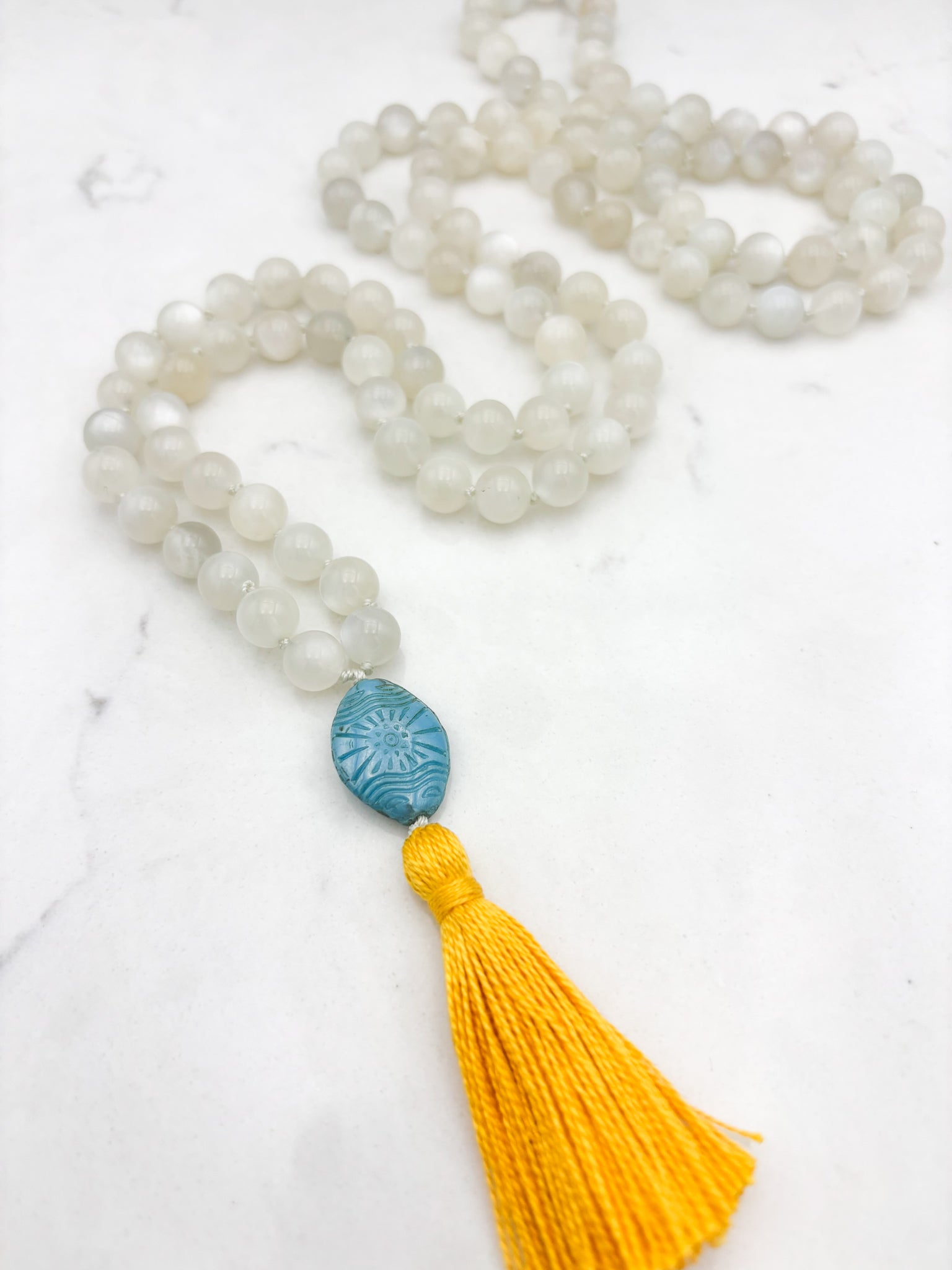 moonstone gemstone mala necklace with carved blue glass guru bead and yellow tassel | handmade in boulder, colorado | radiant malas