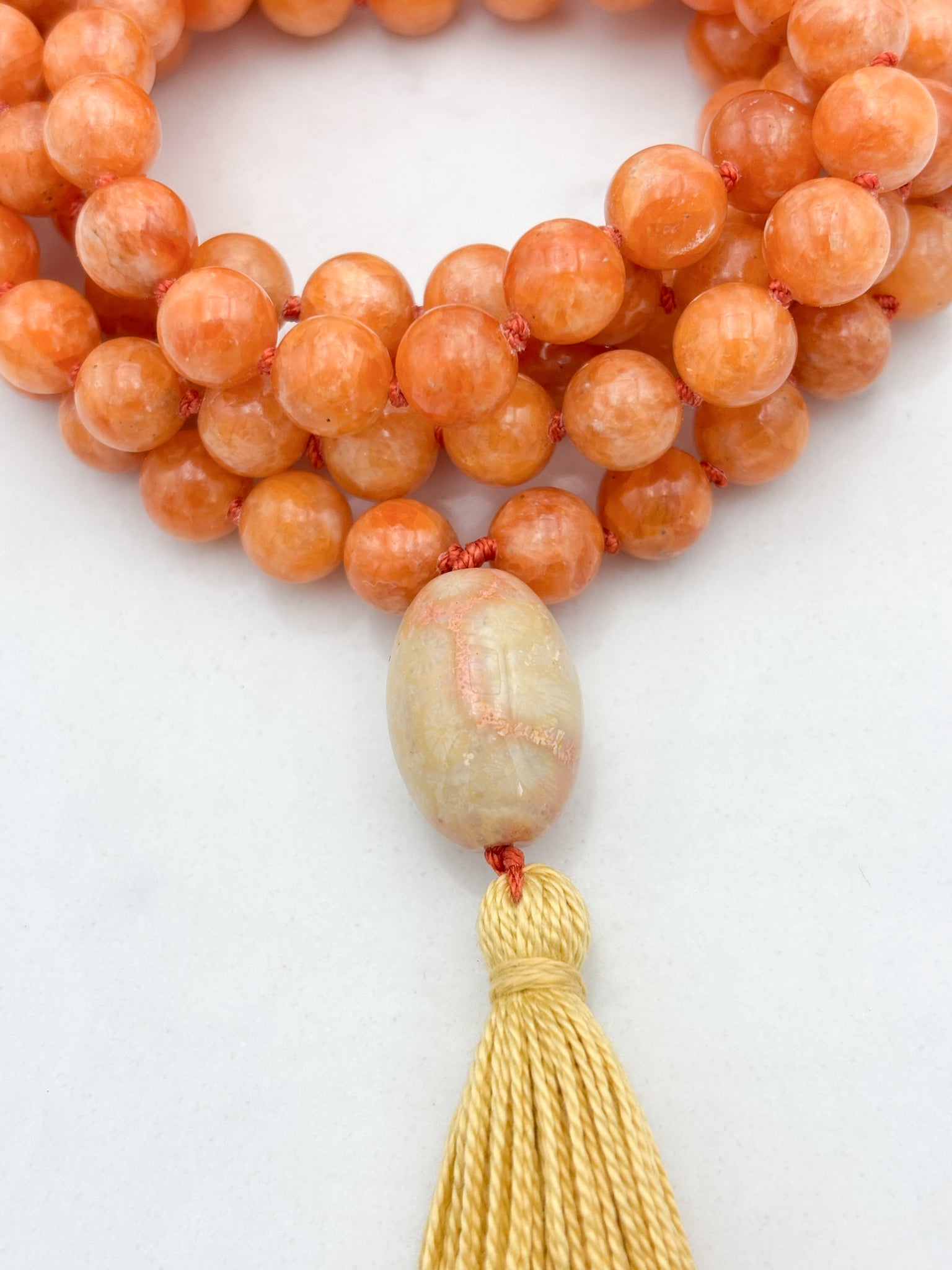 orange calcite gemstone mala with fossil coral guru bead and yellow tassel | radiant malas | handmade in boulder, colorado